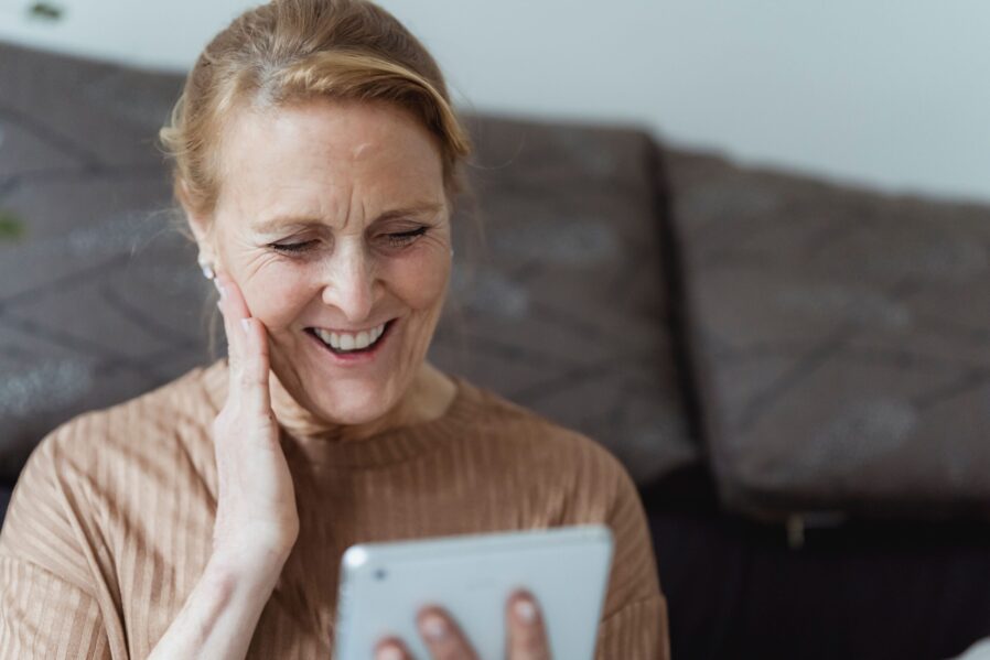 Smiling patient responds to online chat with coordinated care nurse.
